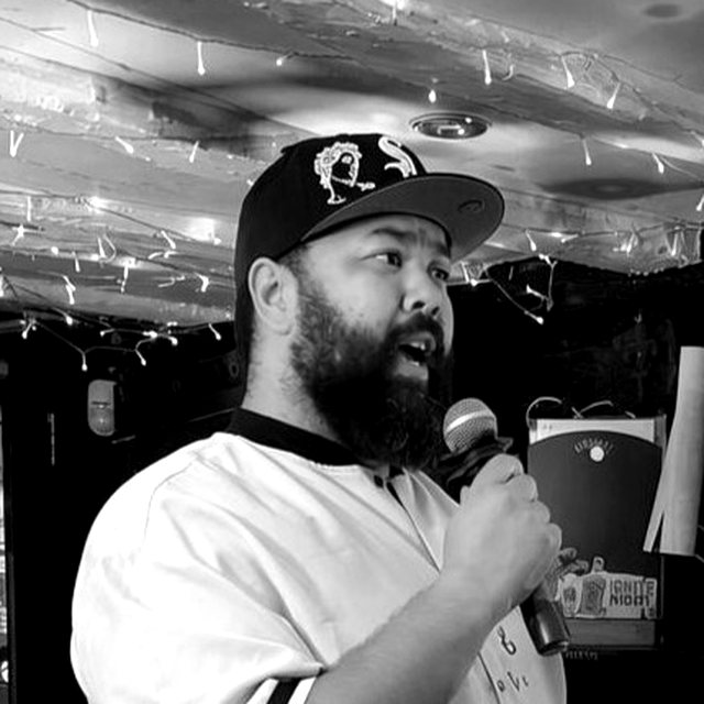 Kyle Wilson singing into a microphone, in black and white